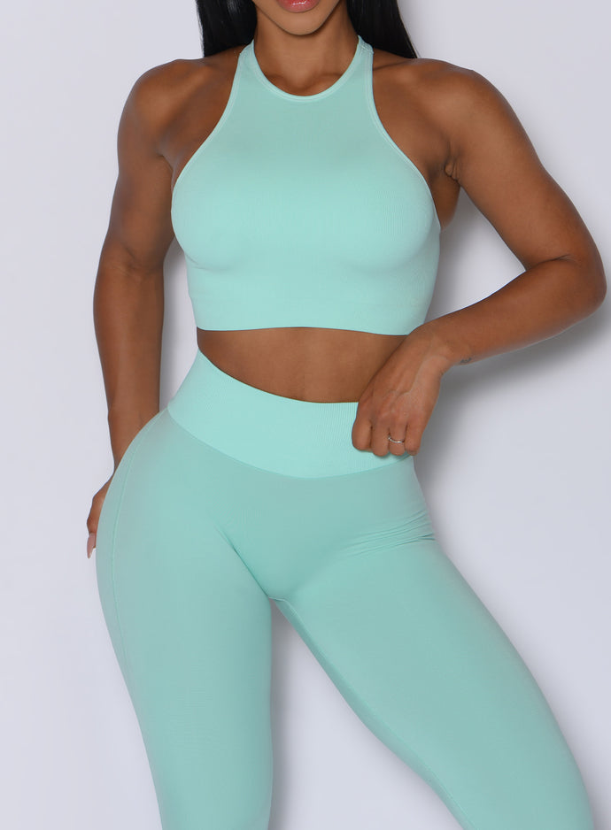 Zoomed in front profile view of a model wearing our Lifter Seamless Bra and the matching leggings in Spring Mint color