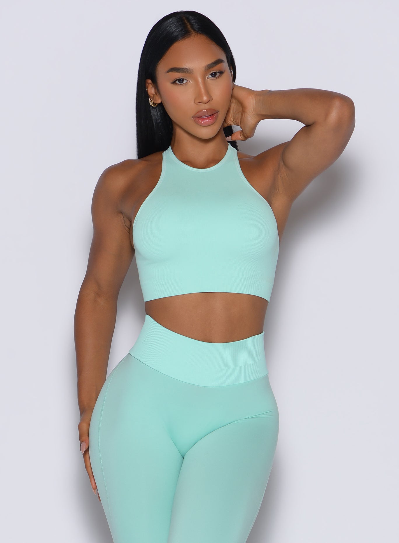 front profile view of a model wearing our Lifter Seamless Bra and the matching leggings in Spring Mint color