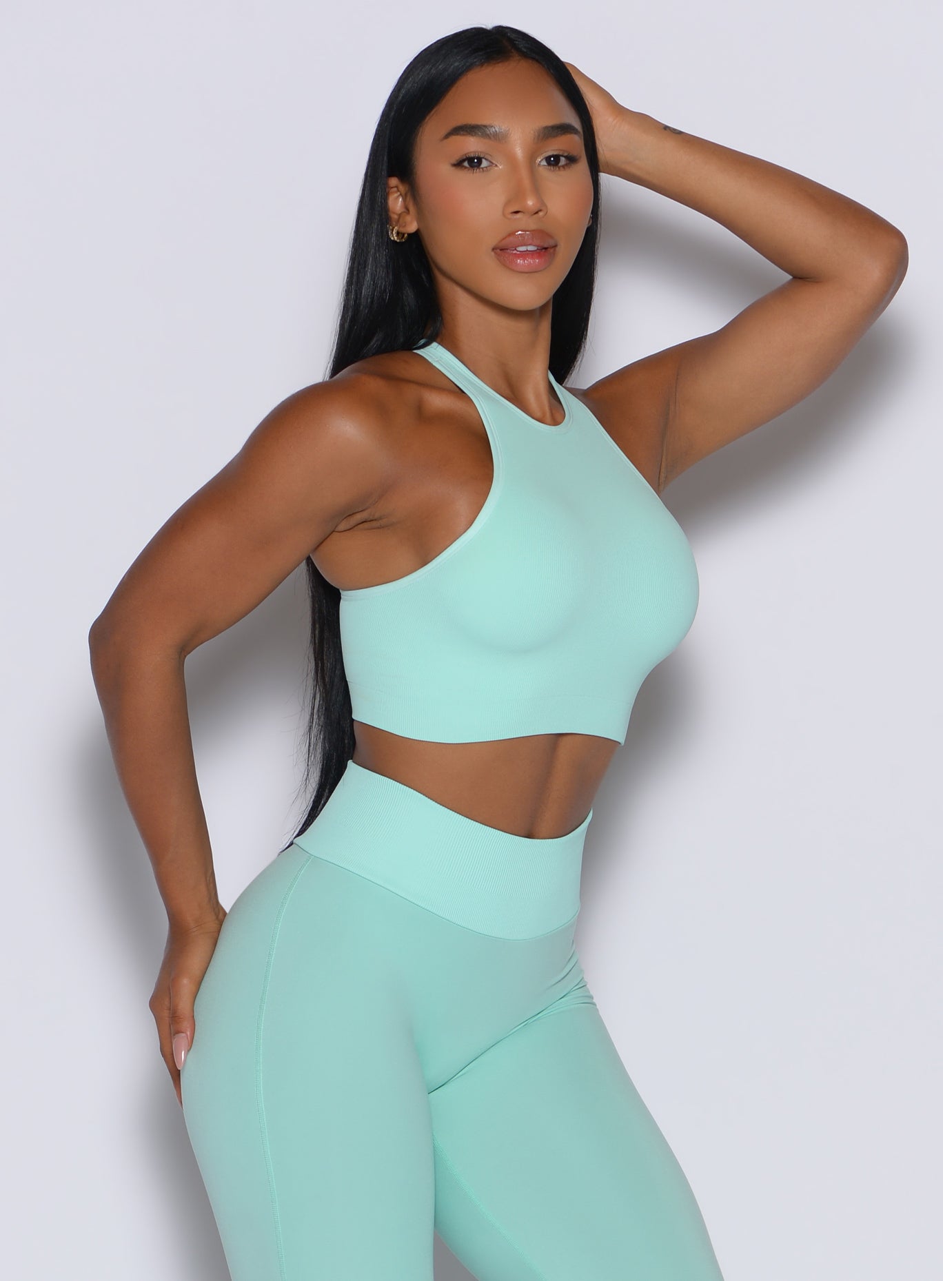 Right side view of a model facing to her right wearing our Lifter Seamless Bra and the matching leggings in Spring Mint color