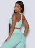 left side view of a model facing to her left wearing our Lifter Seamless Bra and the matching leggings in Spring Mint color