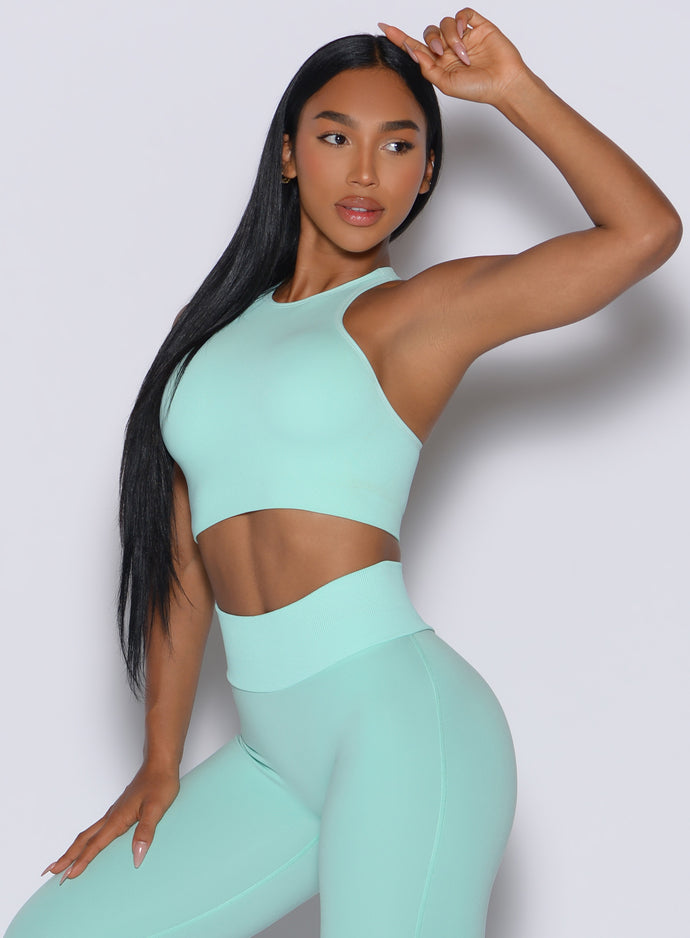 front profile view of a model angled slightly to her right wearing our Lifter Seamless Bra and the matching leggings in Spring Mint color