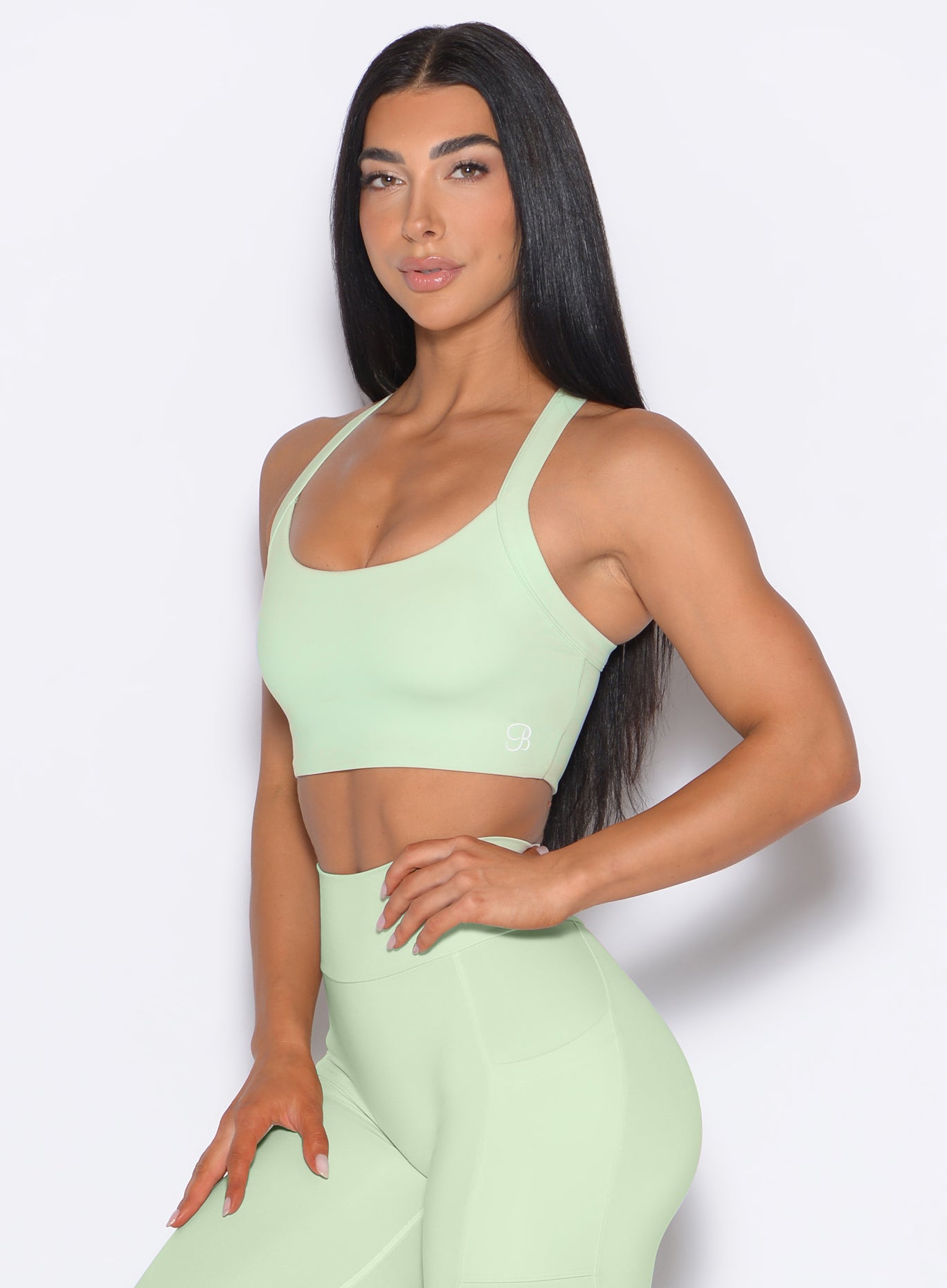 left side profile view of a model wearing our High Impact Bra in Cool Matcha color and the matching leggings
