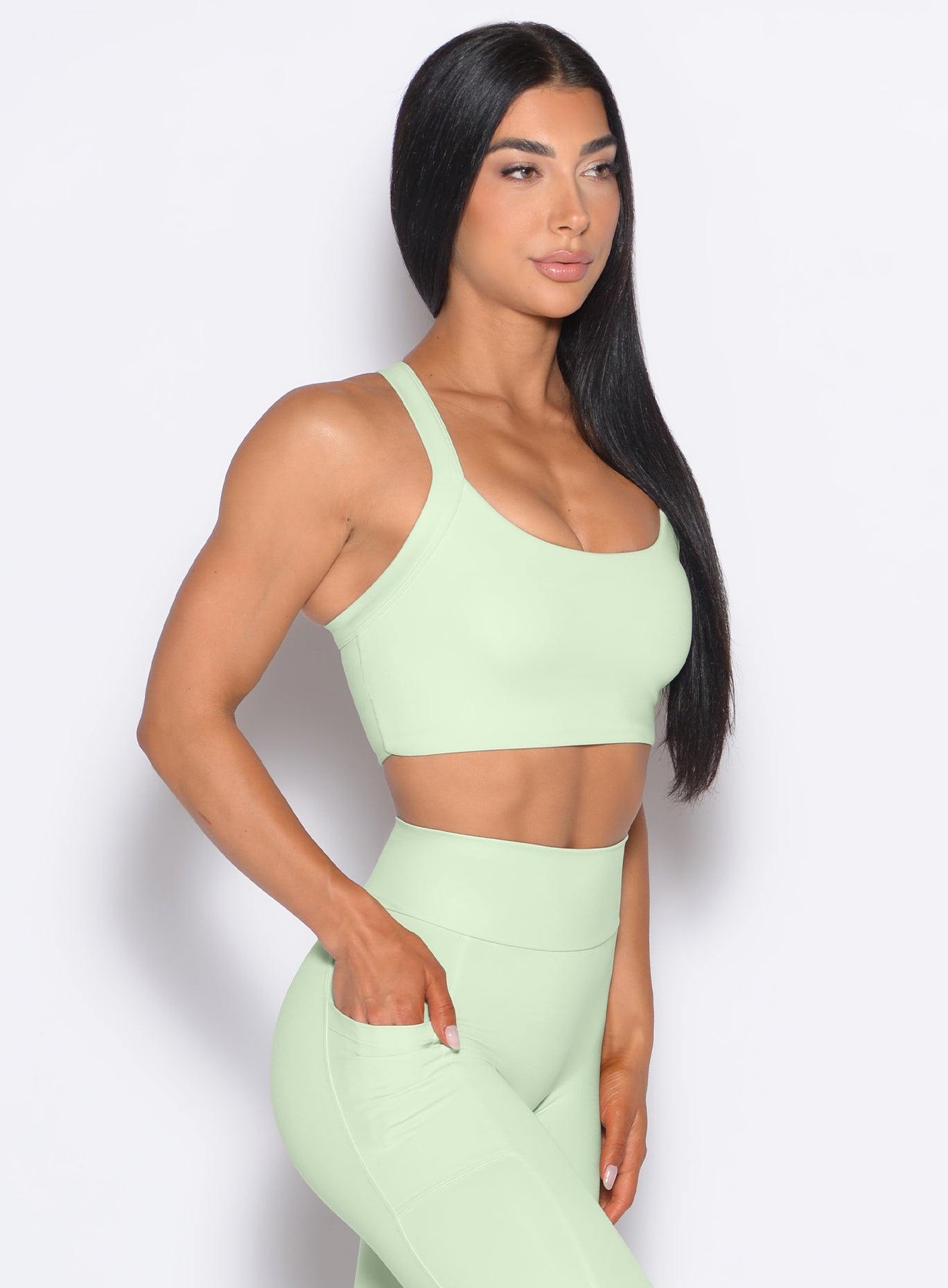 right side profile view of a model wearing our High Impact Bra in Cool Matcha color and the matching leggings
