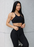 Front side close up profile view of a model wearing our black high neck crop bra and a matching leggings 