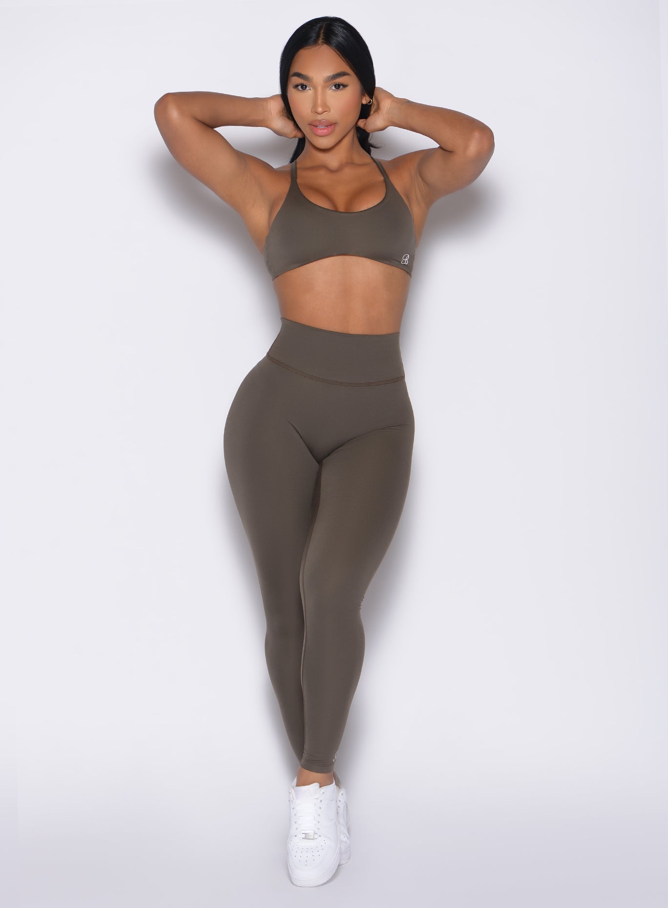 front profile view of a model in hair tying pose wearing the Internal Scrunch Leggings in winter oak color