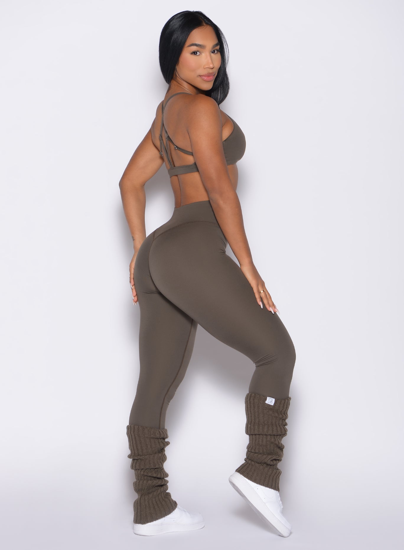 right side profile view of a model looking over her shoulder wearing the Internal Scrunch Leggings in winter oak color