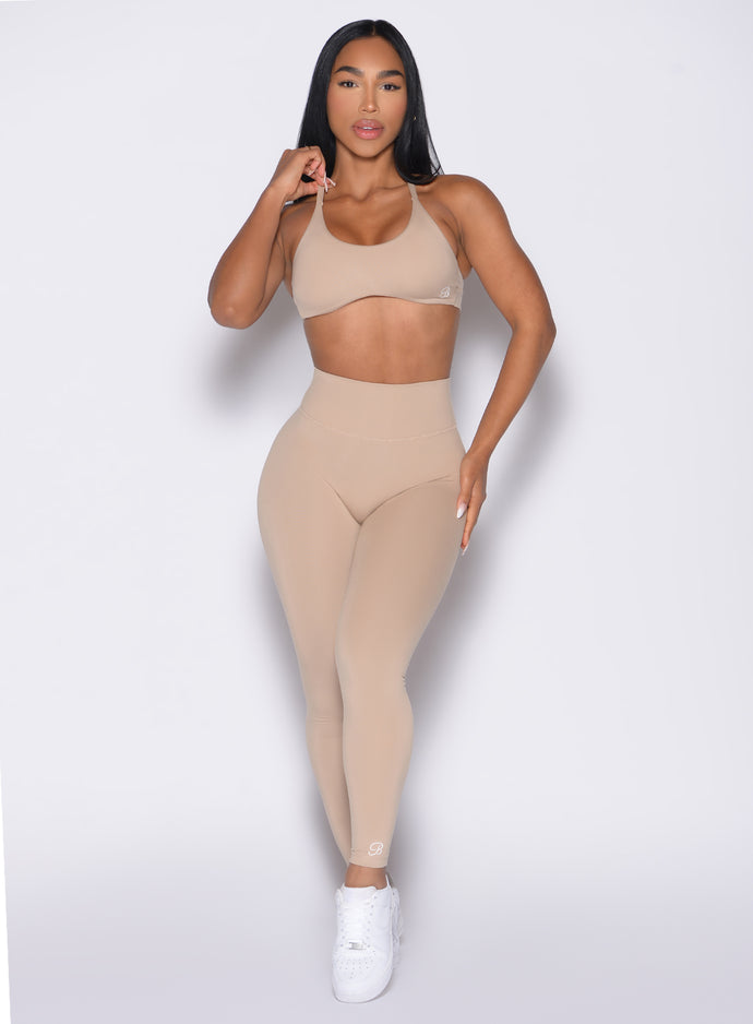 front profile view of a model wearing the Internal Scrunch Leggings in Glacial beige color paired with the matching bra