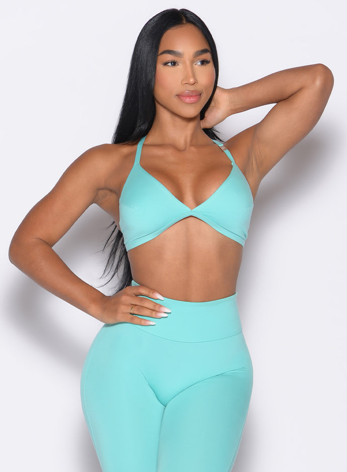 front profile view of a model with one hand on her waist wearing the Kini Bra in aquatic awe color