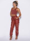 front left side profile view of our model with both hands inside the pockets wearing the Liquid Cargos in brick red color