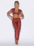 front profile view of our model adjusting the waistband wearing the Liquid Cargos in brick red color paired with the matching Fab bust bra