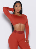 front profile view of our model resting one hand on her thigh wearing the Bombshell Active Pullover in red ochre color