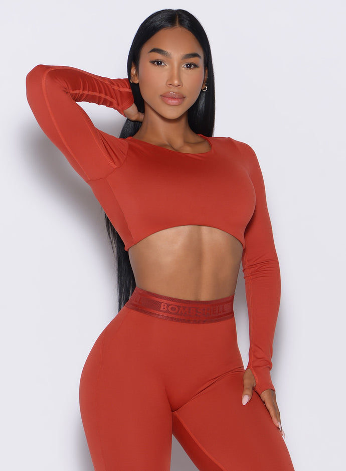 front profile view of our model resting one hand on her thigh wearing the Bombshell Active Pullover in red ochre color