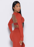 right side profile view of our model looking over her shoulder wearing the Bombshell Active Pullover in red ochre color