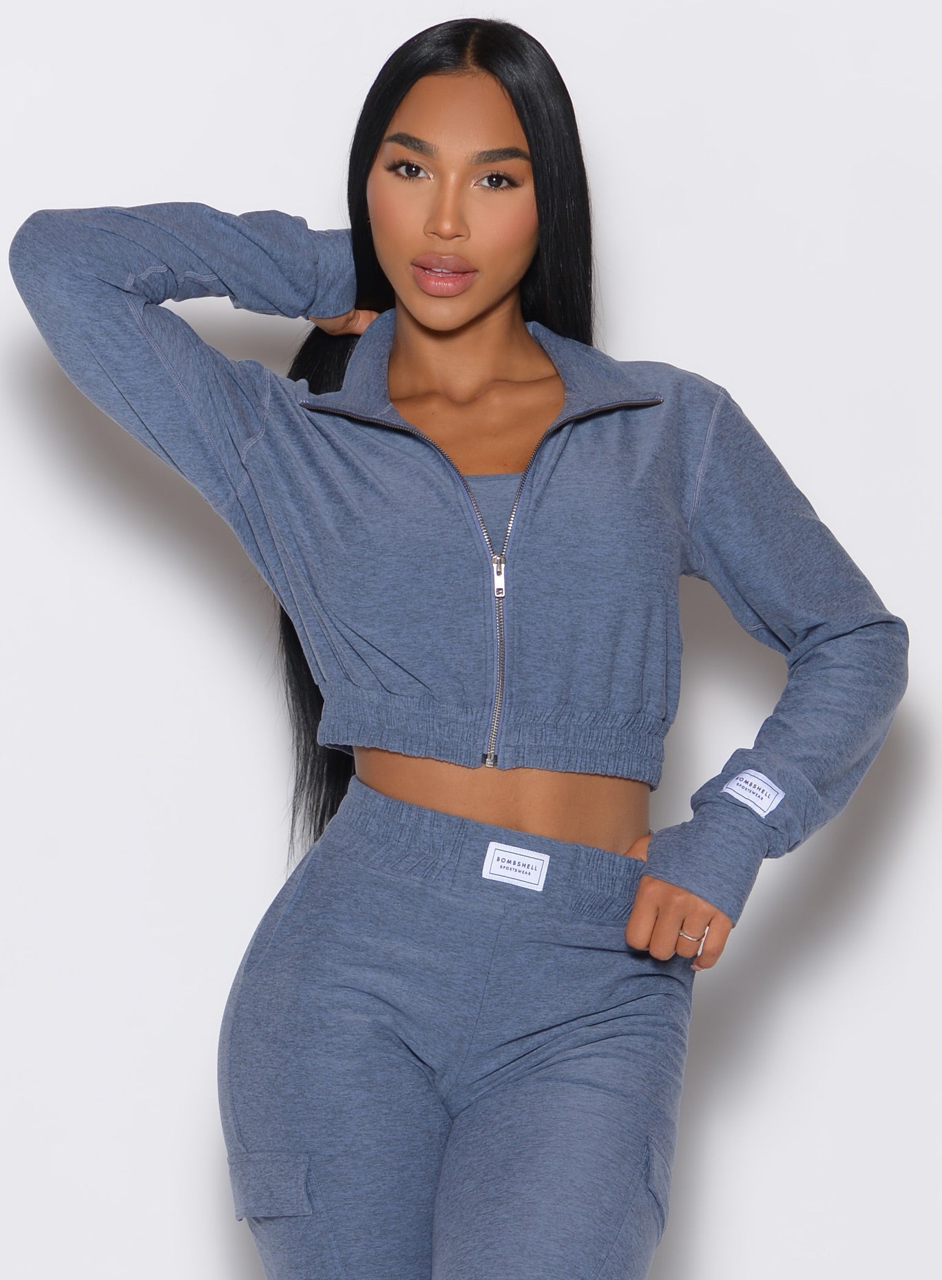 Front profile view of our model wearing the Cloud Crop Jacket in twilight color with one hand on the waist of the matching joggers and the other hand on her hair