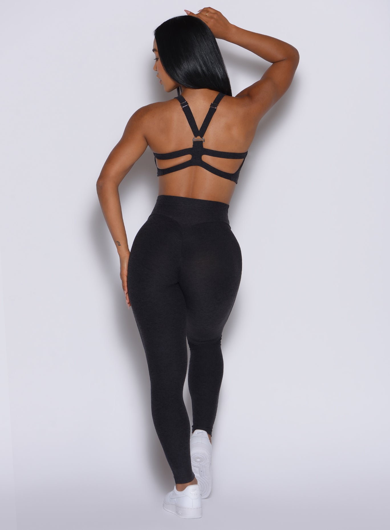 back profile of model wearing the Movement Leggings in black Onyx color and a matching sports bra