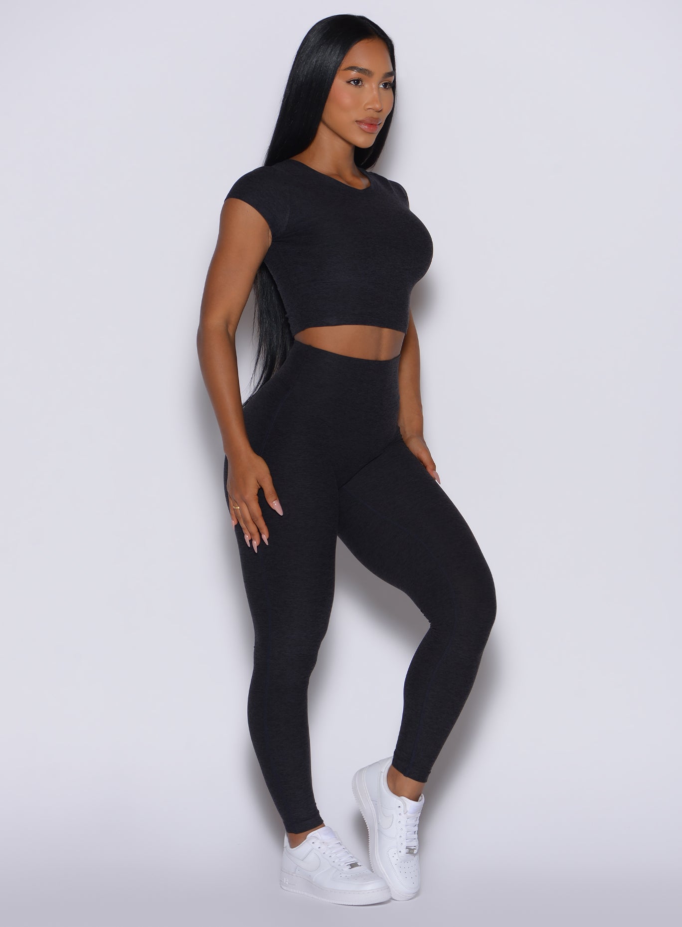 front profile view of a model angled left wearing our Movement Leggings in Onyx color and a matching Tee