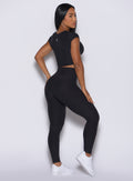 back profile of model facing to her right wearing the Movement Leggings in Onyx  color and a matching Tee