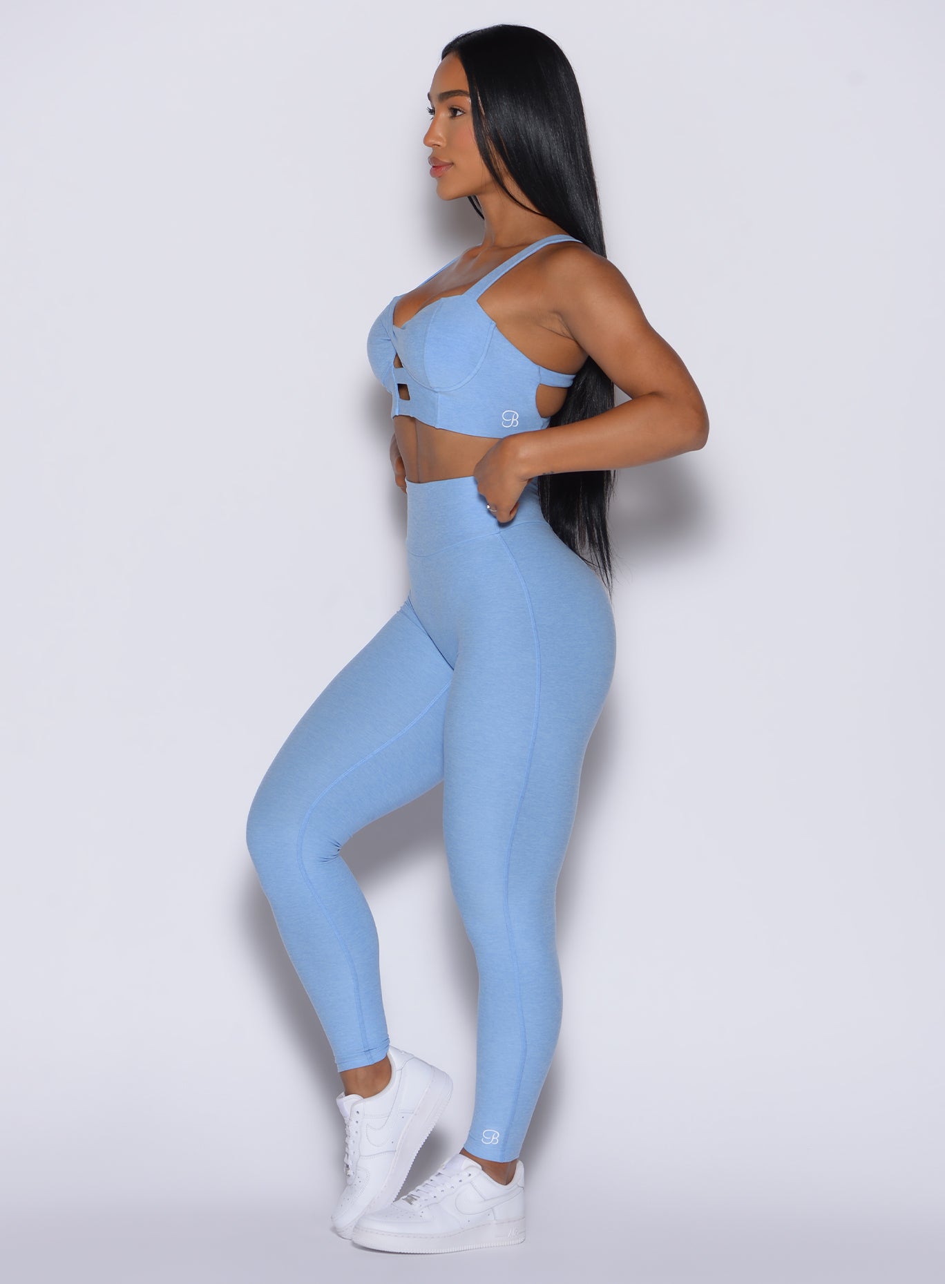 Left side view of a model facing forward wearing our Movement Leggings in Bright Hydrangea color and a matching Sports Bra