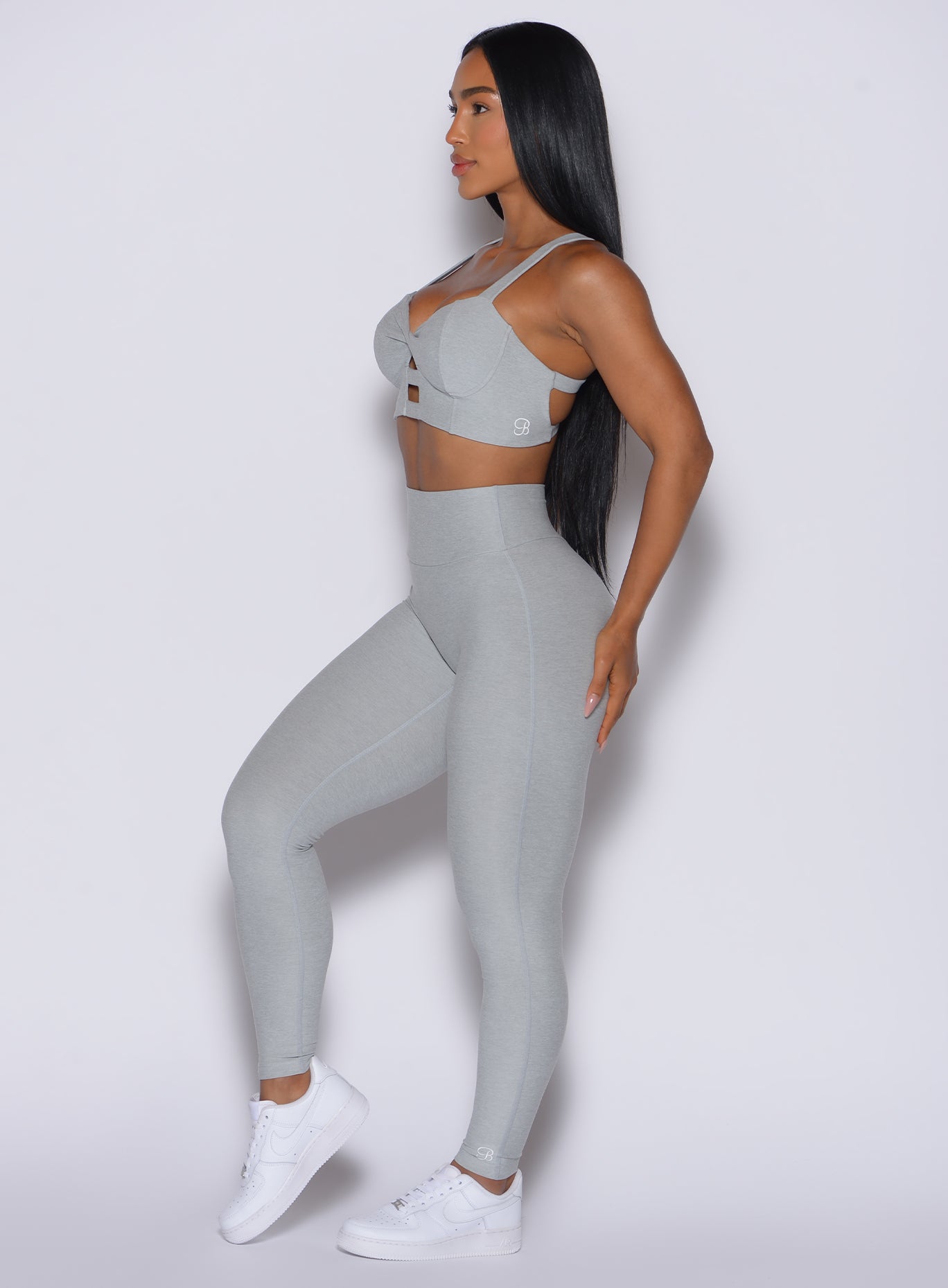 Left side view of model facing forward wearing the Movement Leggings in Light Cloud color and a matching Sports Bra