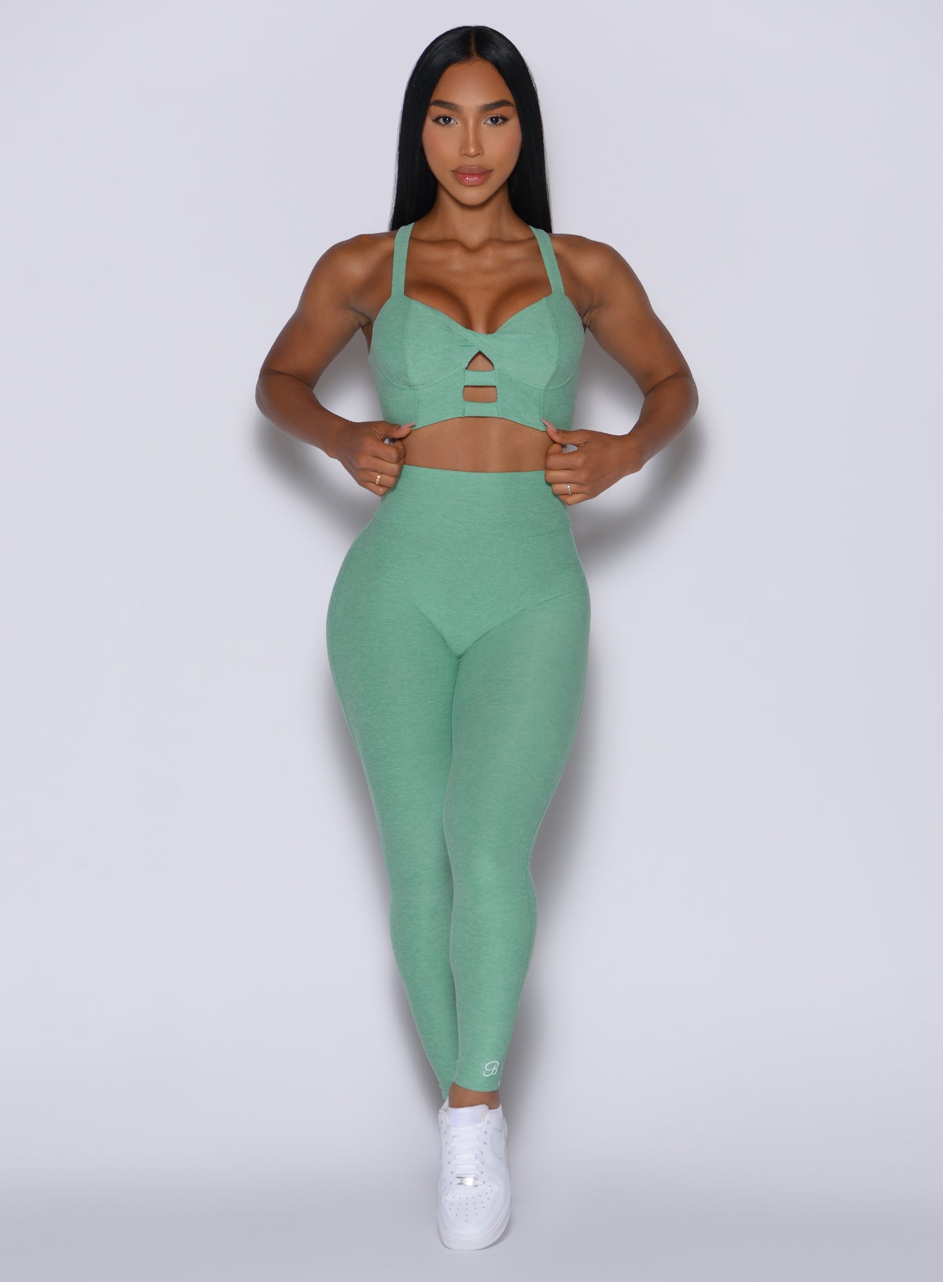 front profile view of a model wearing our Movement Leggings in Sage color and a matching Sports Bra