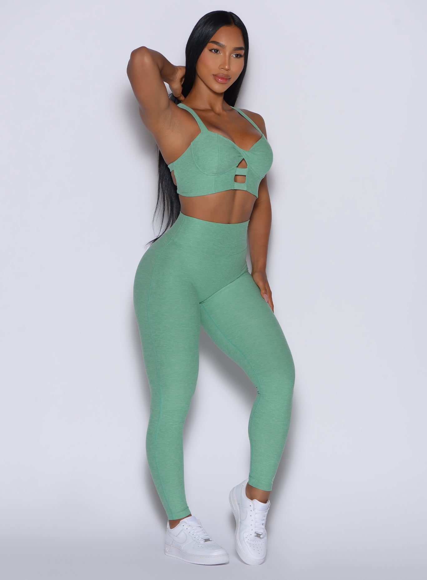 front profile picture of a model angled slightly to her left in our Movement Leggings in Sage color and a matching Sports Bra