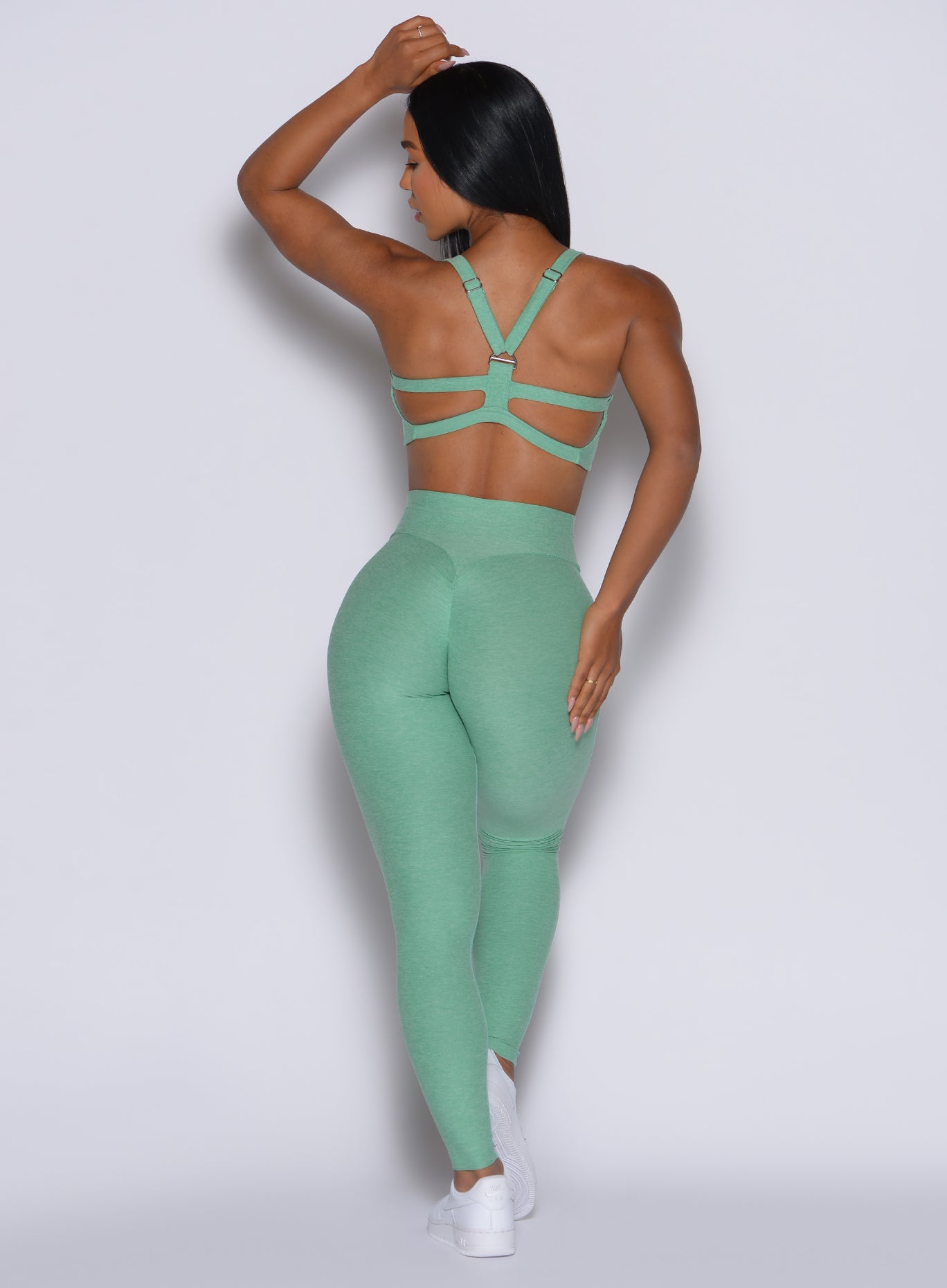 back profile picture of a model wearing our Movement Leggings in sage color along with the matching bra
