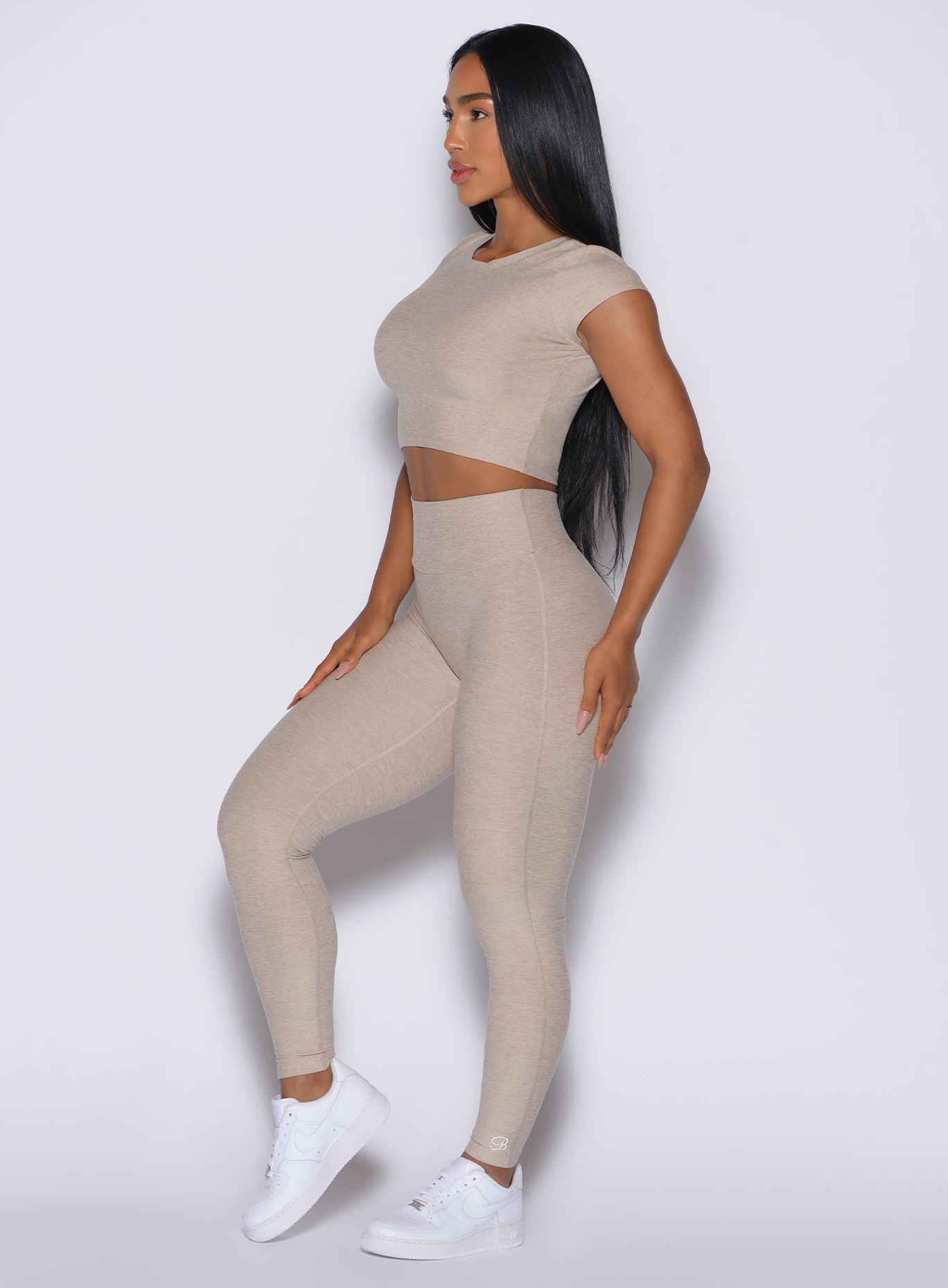 Right side view of a model in our Movement Leggings in Taupe color and a matching Tee 