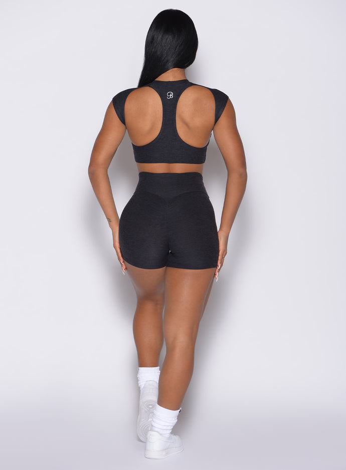 back profile view of a model with both hands on her thighs wearing the Movement Shorts in Heathered Black color