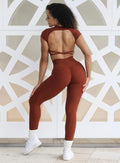 Back profile view of a model facing to her left wearing our open back tee in Cinnamon color and a matching leggings