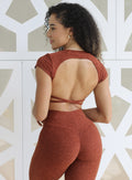 Back profile view of a model facing to her left wearing our open back tee  in Cinnamon color and a matching leggings 