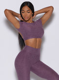 front profile view of a model in our open back tee in Regal Purple color and a matching leggings