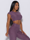 Right side profile view of a model facing forward wearing our open back tee in Regal Purple color and a matching leggings