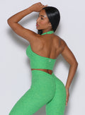 back profile view of a model wearing our longline backless bra in Neon Miami Beach color along with a matching leggings