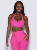 Front profile view of a model wearing our backless bra in Neon Pink Sorbet color along with the matching leggings