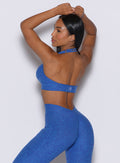 back profile view of a model wearing our backless bra in Neon blue rave color along with the matching leggings