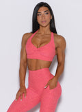 Front profile view of a model wearing our backless bra in Neon Tangerine Shock color along with the matching leggings