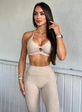 front profile view of a model wearing our tiny twist bra in taupe color along with the matching curves leggings