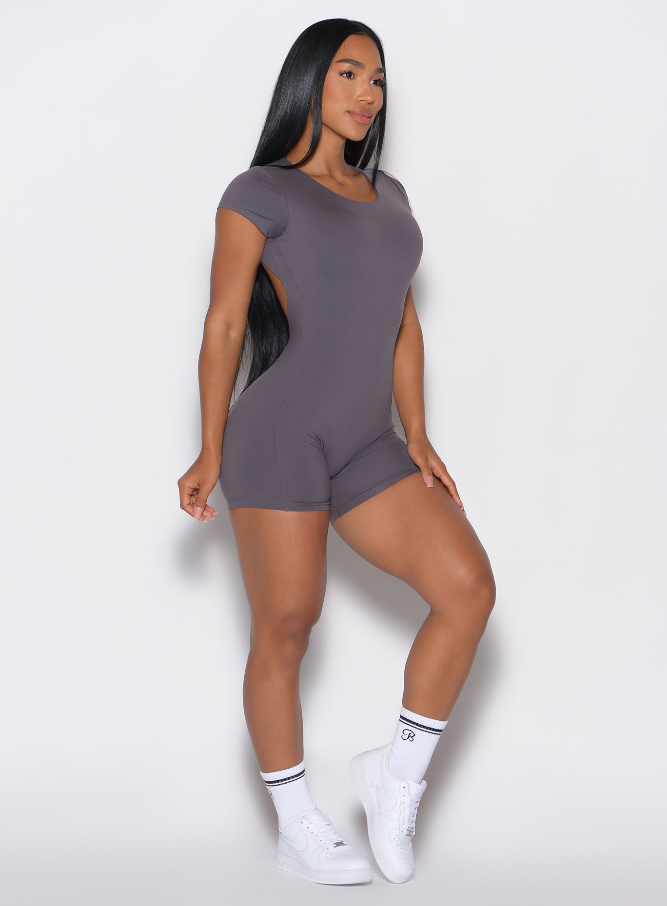 Right side profile view of a model wearing our Open Back Tee Bodysuit Short in gray smoke color