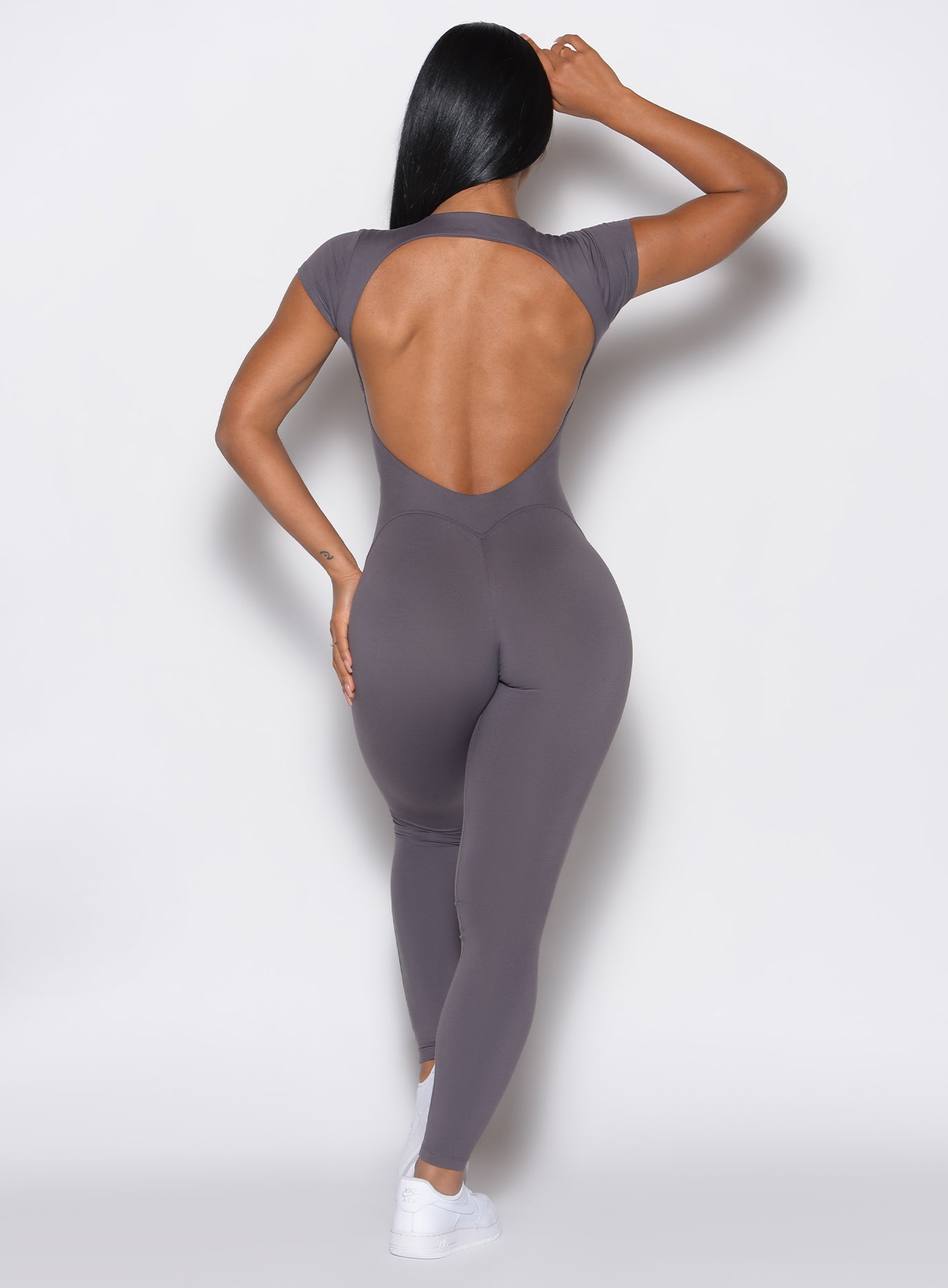 back profile picture of a model wearing our open back tee bodysuit in gray smoke color