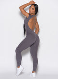 left side profile view of a model facing to her left wearing our open back tee bodysuit in gray smoke color