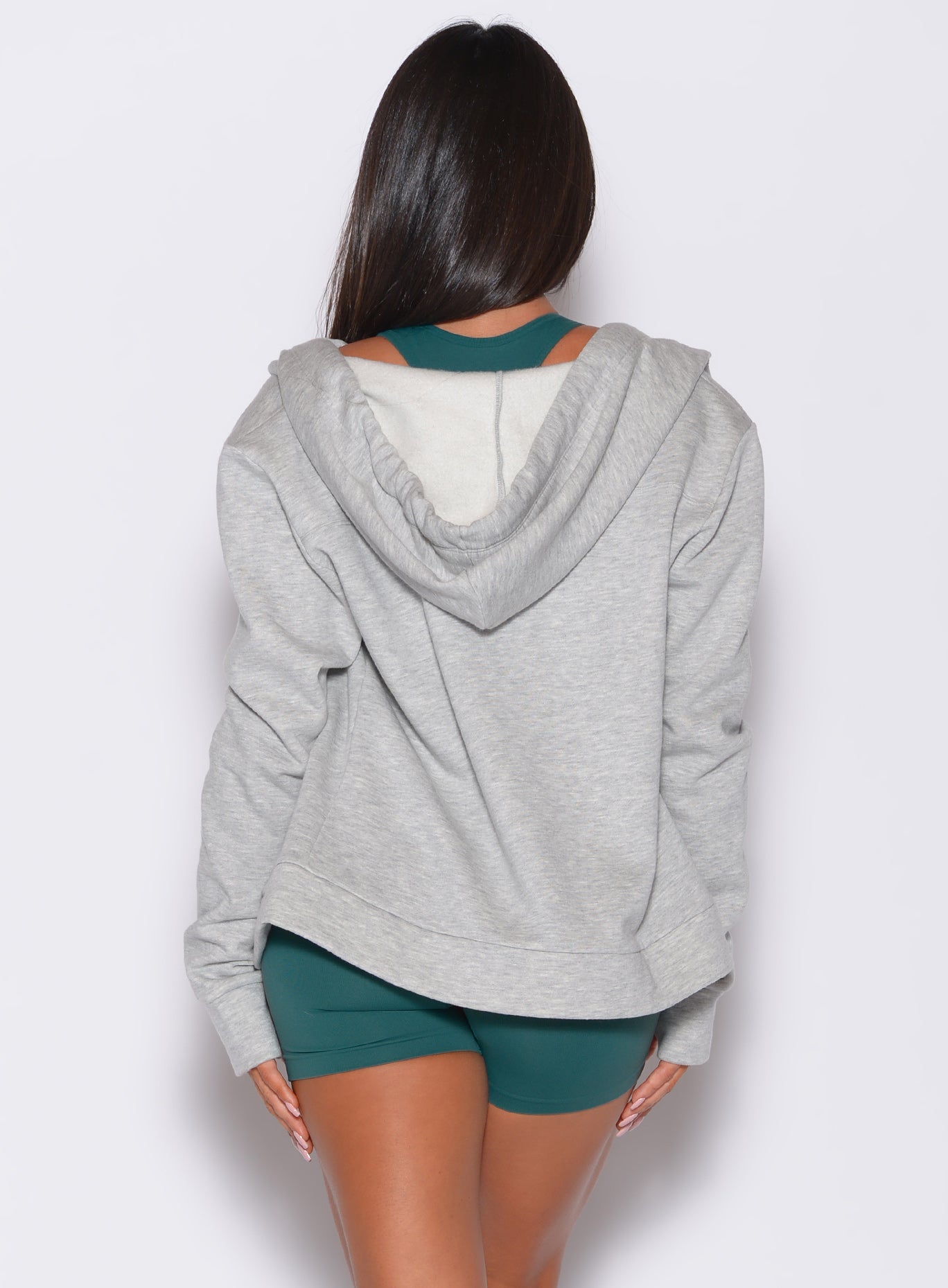 back profile view of a model wearing our heather gray oversized hoodie, along with shorts and a bra in rainforest color 