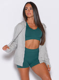 front profile view of a model facing to her right  wearing our heather gray oversized hoodie, along with shorts and a bra in rainforest color