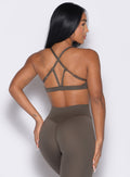 back profile view of a model with both hands resting on her thighs wearing the Passion Sports Bra in winter oak color