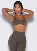 front profile view of a model in a hair tying pose wearing the Passion Sports Bra in winter oak color