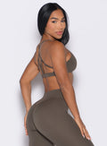 right side profile view of a model looking over her shoulder wearing the Passion Sports Bra in winter oak color