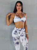 Front  profile view of a model posing in our our topnotch bra in tie dye white gray color and a matching leggings