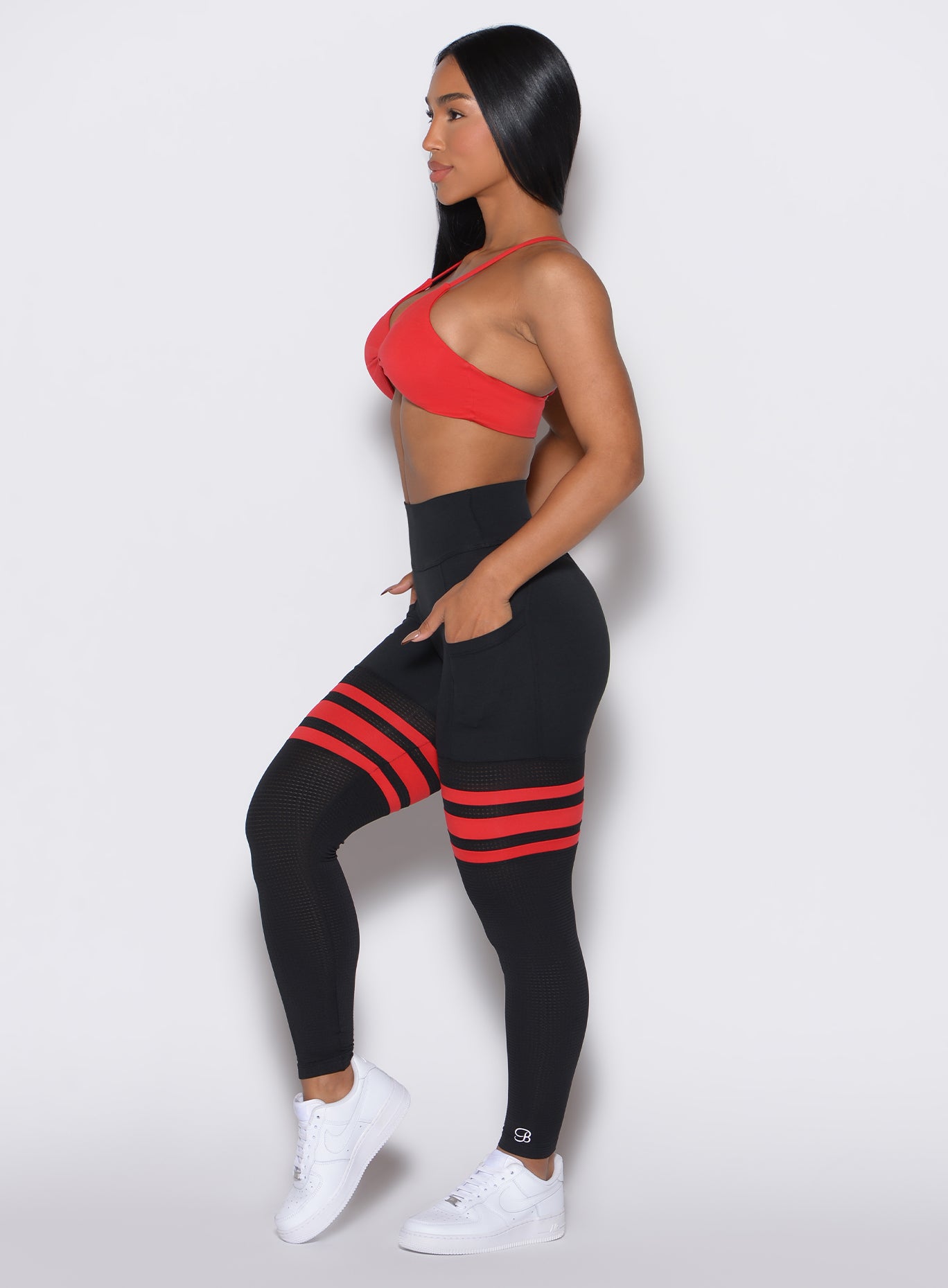 Left profile shot of a model wearing the Perform Thigh Highs in Black Fire color along with a matching sports bra 