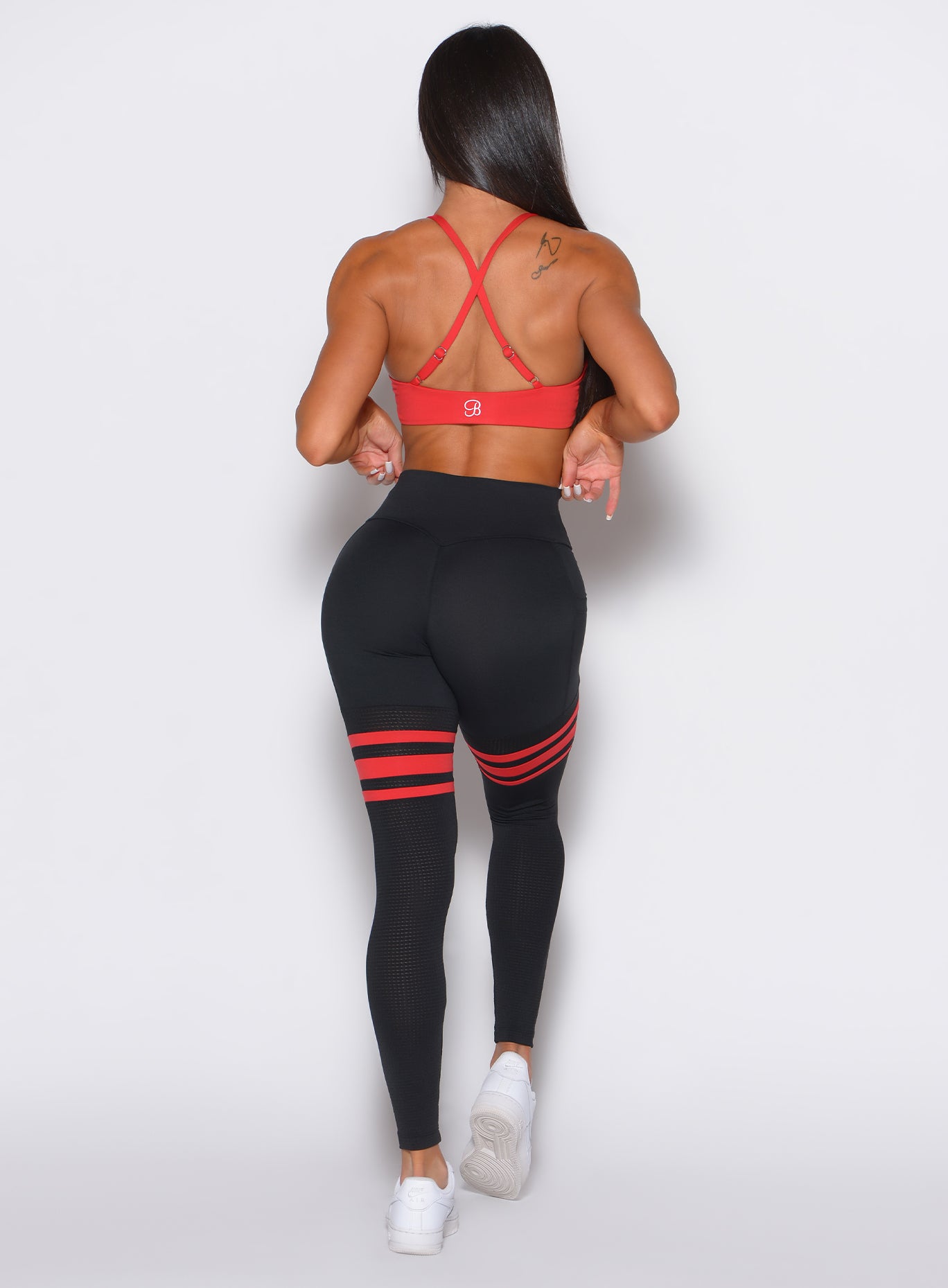 Back profile view of a model wearing the Perform Thigh Highs in Black Fire color  along with a matching bra