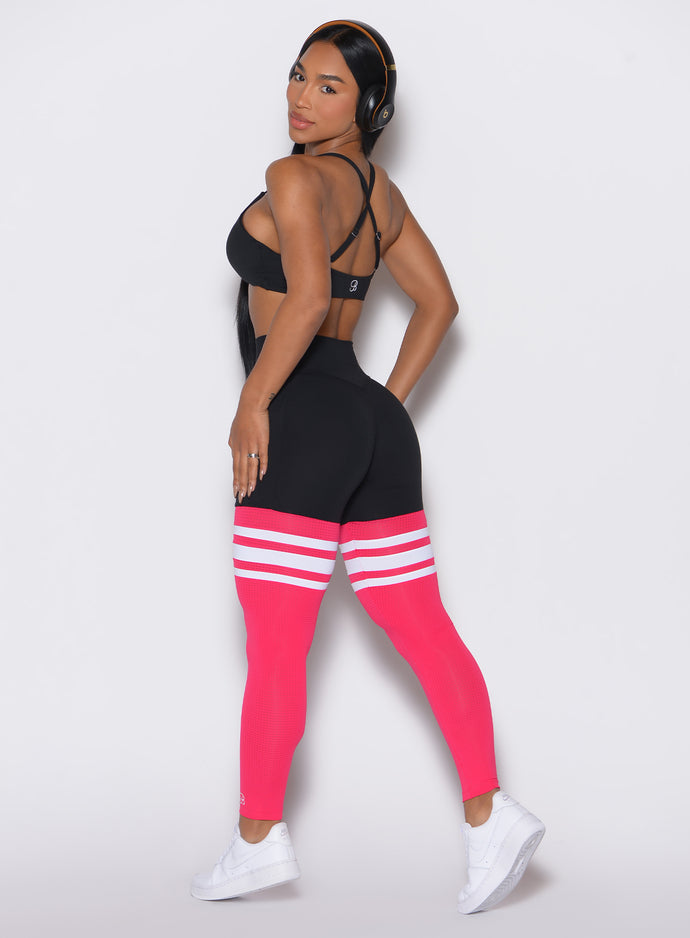 Back left side profile view of a model wearing the Perform Thigh Highs in Black Sky color along with a black sports bra