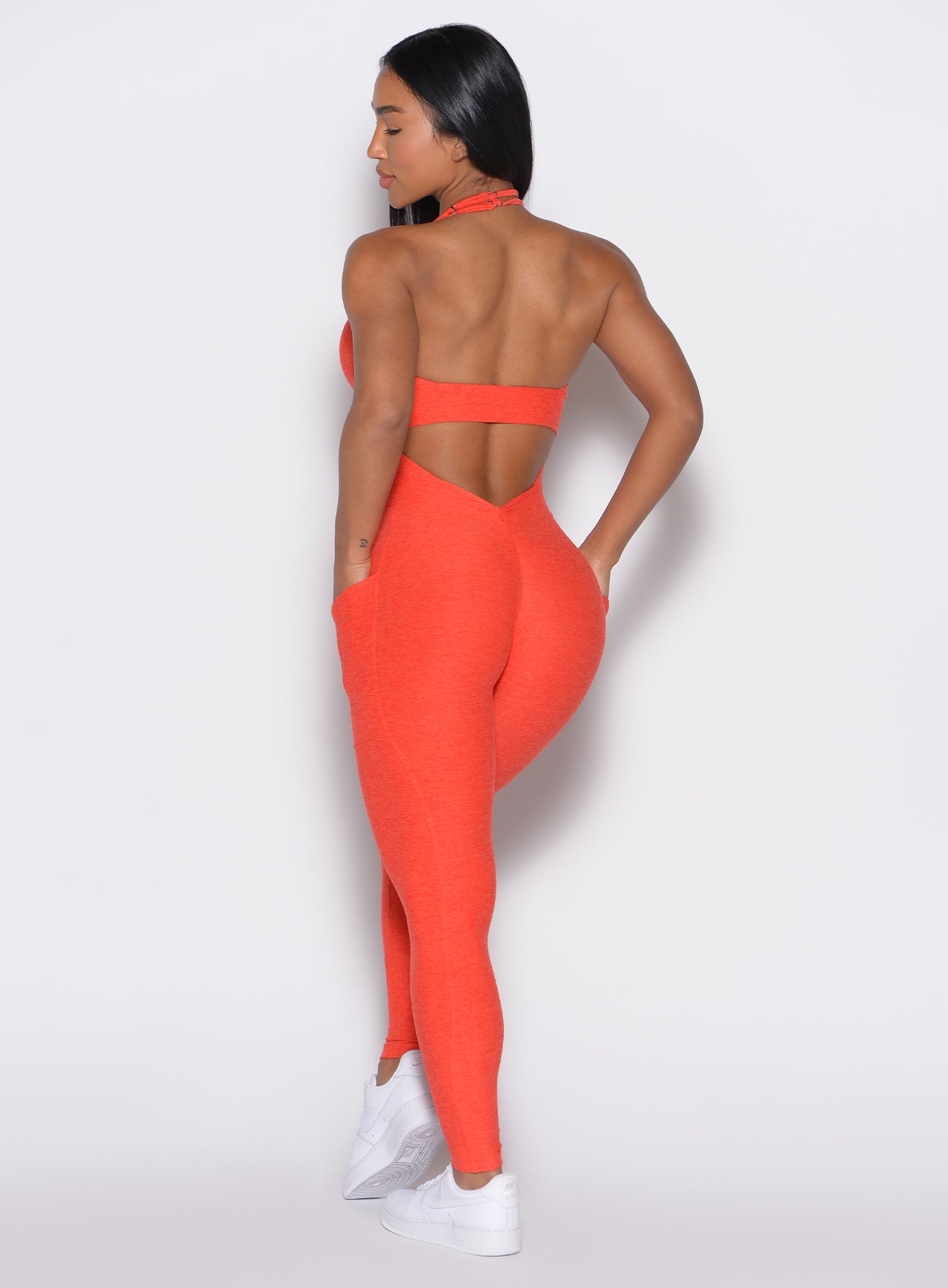 back profile view of a model wearing our Backless Pocket Bodysuit in apricot color